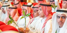 A group of young Saudi men in traditional attire holding green plants. 